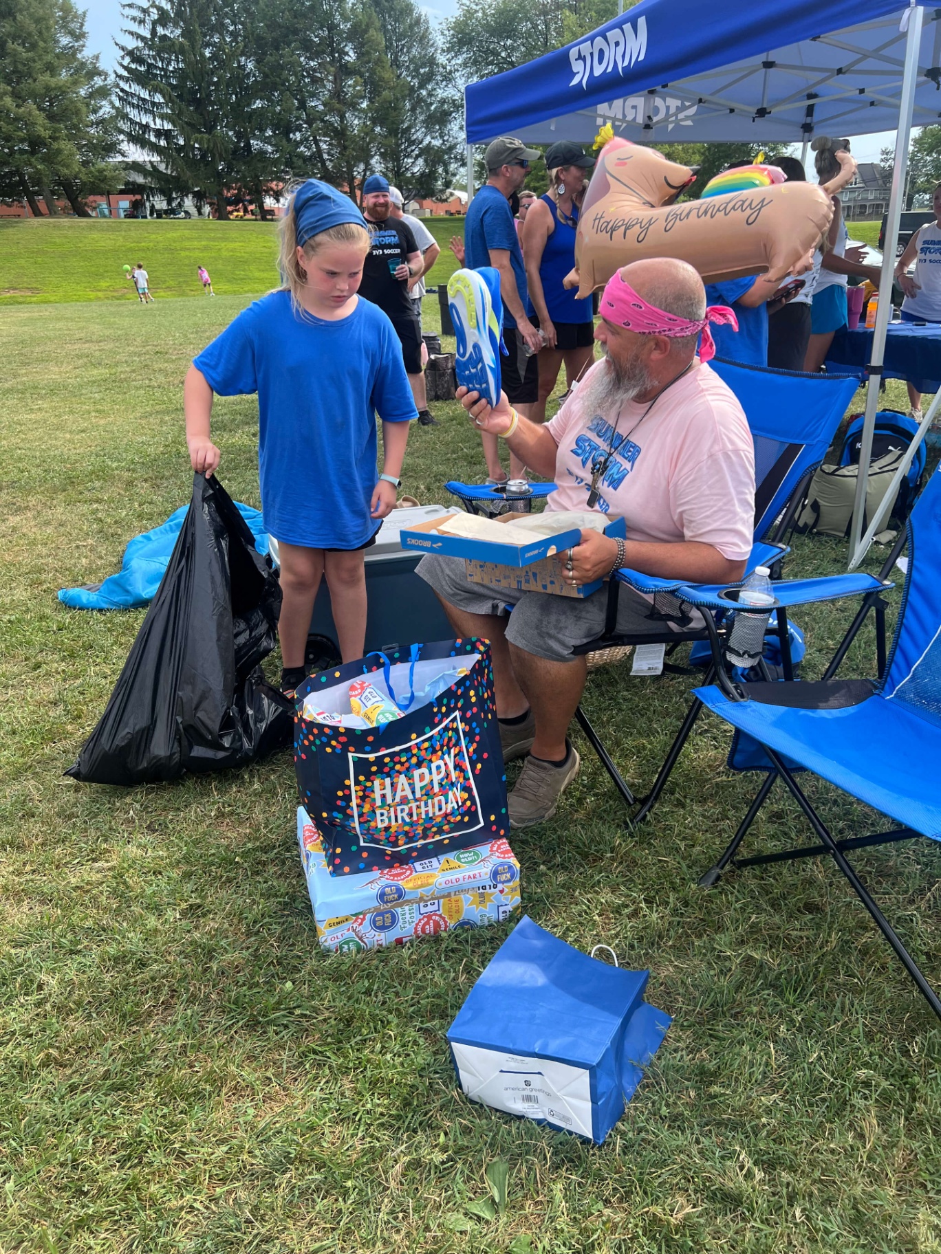 2025 — Coach opening birthday gifts under the Storm tent