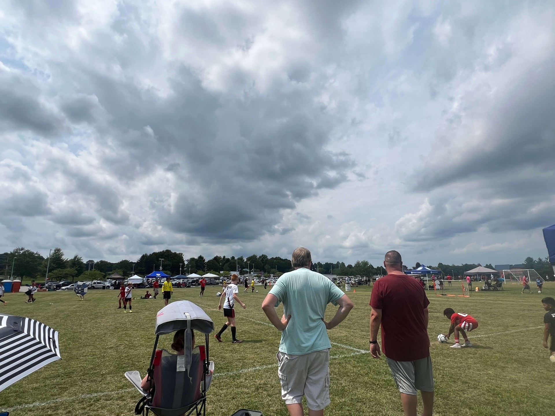 2025 — Parents watching matches under a moody storm sky