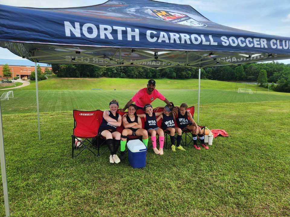 WSA girls team relaxing together under the North Carroll Soccer Club tent