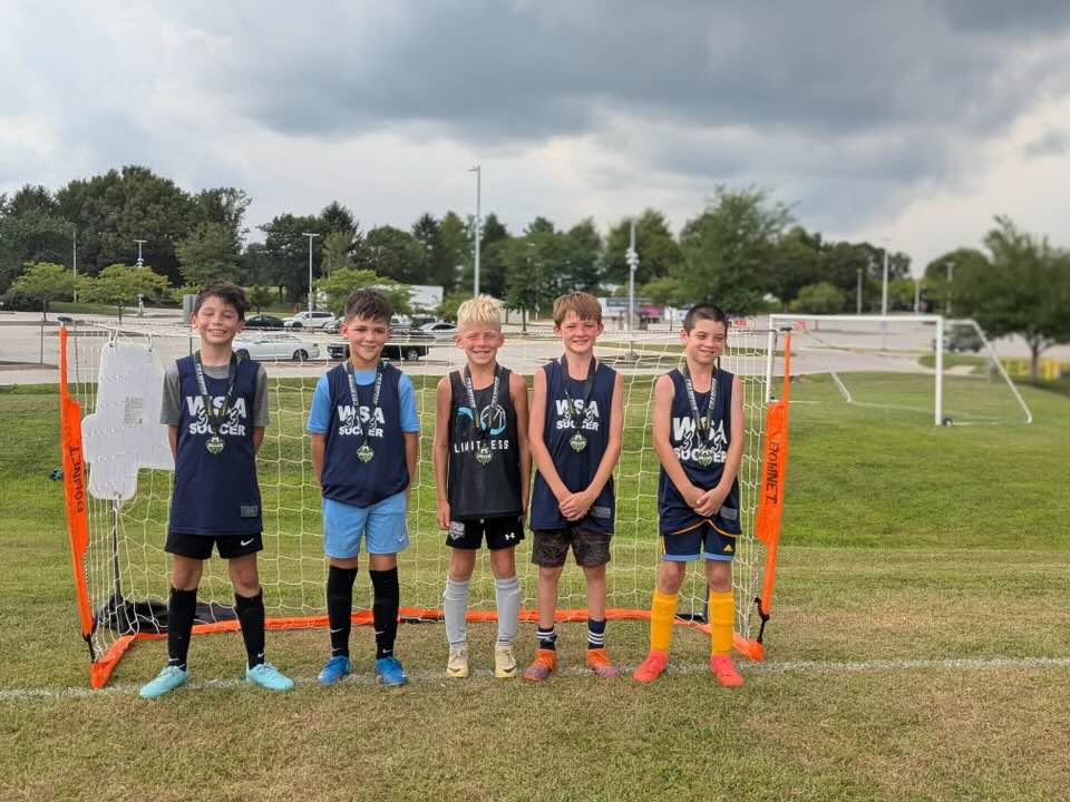 Navy team lined up with medals in front of a small goal