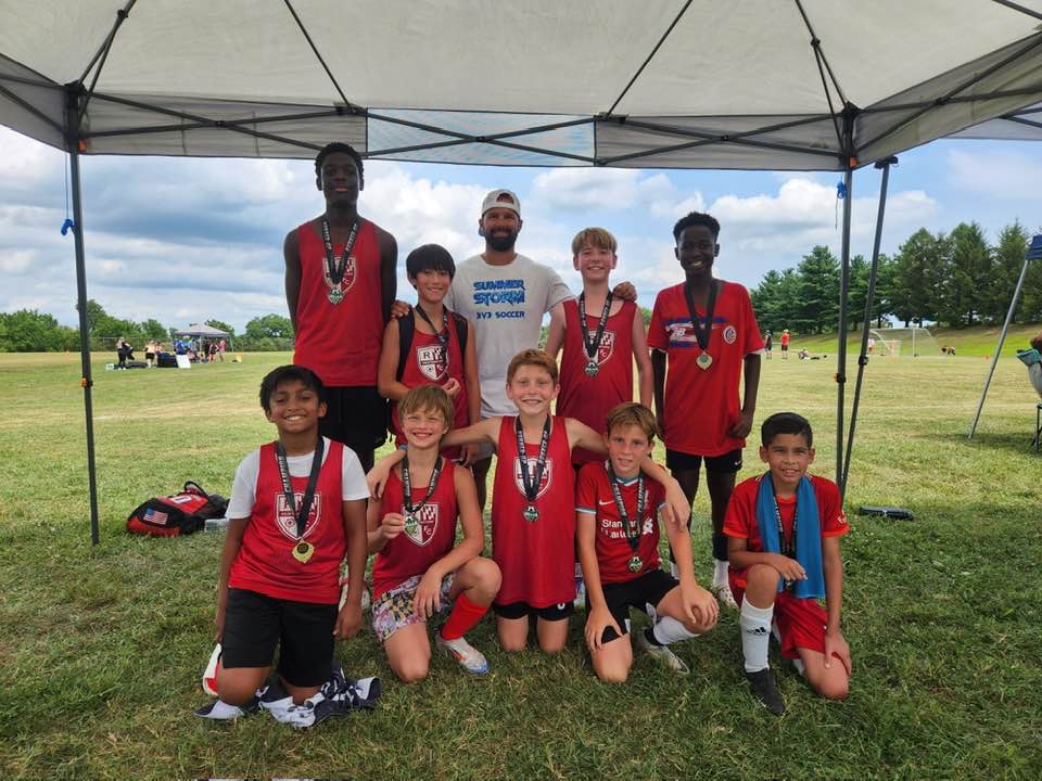 Large red team group with medals under a tournament tent