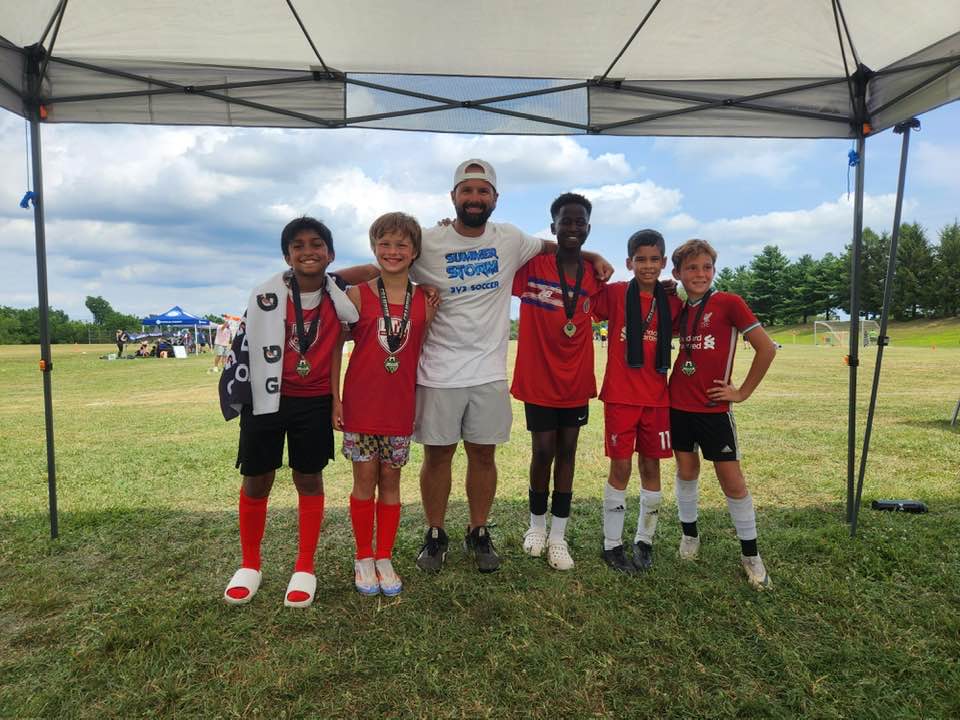 Red team and coach posing with medals after a Summer Storm match
